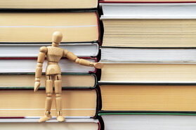 Wooden mannequin standing on the stack of books Wooden mannequin standing on the stack of books
