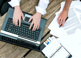 Top view of women's hands with documents and laptop